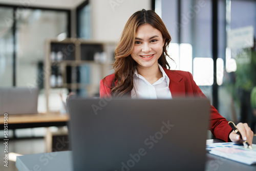 Beautiful young teen asian businesswoman using laptop computer and paperworks with planning working on financial document, tax, exchange, accounting and Financial advisor © Jirapong