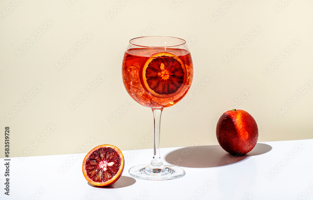 Rosso tonic alcoholic cocktail drink with red vermouth, tonic, orange and ice in wine glass. Beige background, minimalist style, copy space - obrazy, fototapety, plakaty 