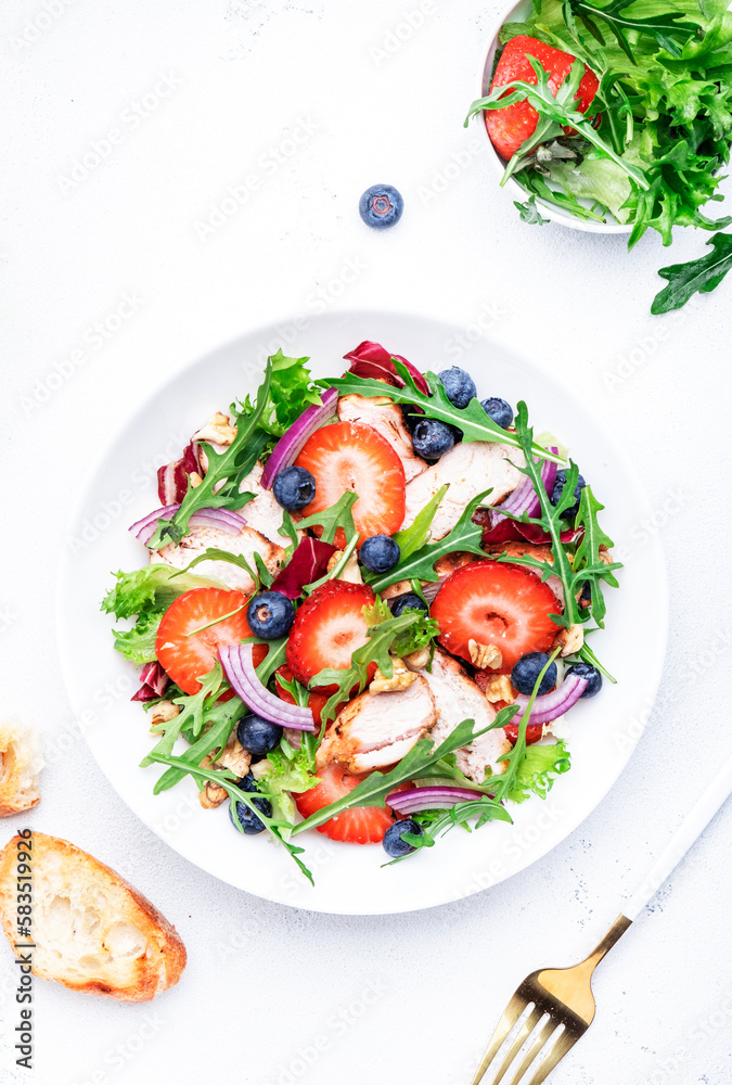 Strawberry, grilled chicken fillet and herbs healthy salad with arugula, blueberries and walnuts, white kitchen table, place for text. Fresh useful dish for healthy eating Strawberry, grilled chicken fillet and herbs healthy salad with arugula, blueberries and walnuts, white kitchen table, place for text. Fresh useful dish for healthy eating