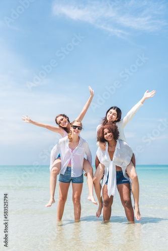 Group of diverse teenager friends enjoying on the beach, spending time together on summer, Young girl enjoy neck riding outdoor activity, Lifestyles on vacation concept. © Platoo Studio