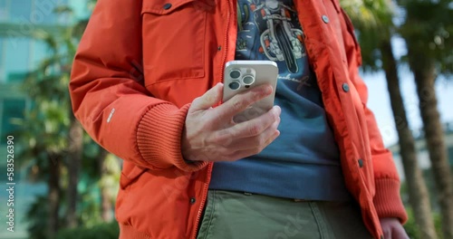 Close Up Of Male Taking Modern Smartphone Out Of Green Cargo Trouser Pocket. Low Angle Shot photo