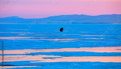 Photographer shoots a sunset among the snow-covered hummocks of Lake Baikal