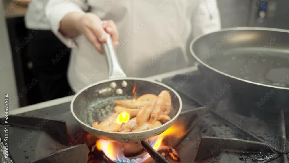 The chef prepares a delicacy sea dish of fried shrimp in a frying pan. stirring food The chef prepares a delicacy sea dish of fried shrimp in a frying pan. stirring food