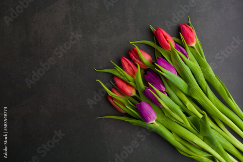 Fresh colorful tulip flowers on dark stone table. Top view  copy space