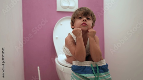 One adorable child seated on toilet seat at bathroom photo