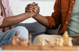 Cropped view of african american man and son holding hands near blurred chess board at home.