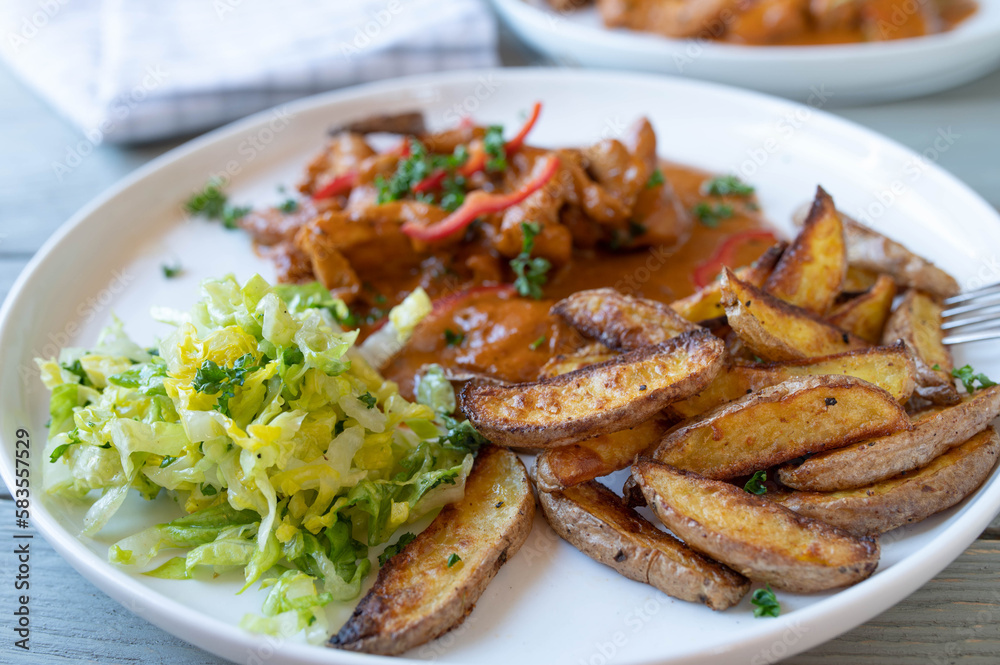 Potato wedges with chicken, sauce and salad on a plate Potato wedges with chicken, sauce and salad on a plate