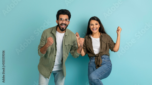 Emotional cheerful multiethnic couple gesturing on blue