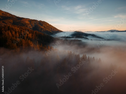 Fototapeta Naklejka Na Ścianę i Meble -  Scenic aerial view of forests and mountains on a foggy day in Mariazell city, Austria