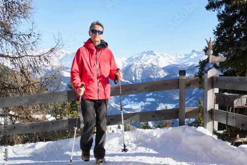 Hiker leaning on a fence in the Swiss Alps in snowy mountain landscape