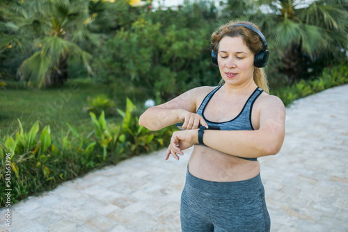 Young plus size woman with smart watch. Girl training in park. Woman with fitness tracker. Copy space and empty space for text