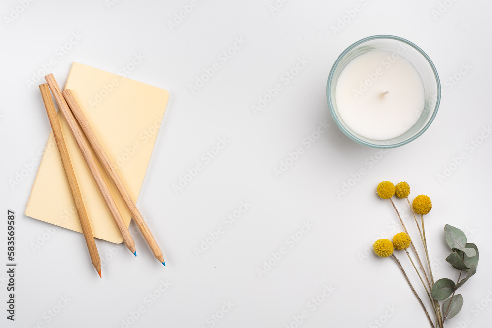 clean workspace with pencils and notebook, candle and flowers on white background. Flat lay clean workspace with pencils and notebook, candle and flowers on white background. Flat lay