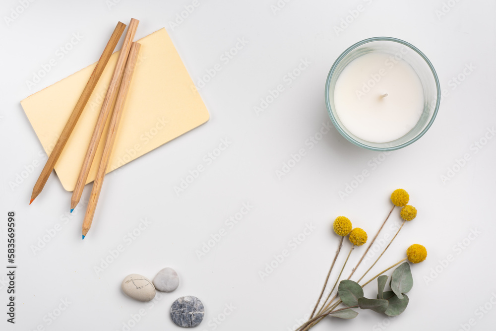 clean workspace with pencils and notebook, candle and flowers on white background. Flat lay clean workspace with pencils and notebook, candle and flowers on white background. Flat lay