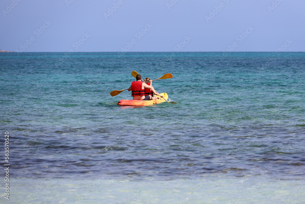Kayaking in the sea, couple wearing life vests rowing with paddles in canoe. Man and woman in one team, travel and water sports