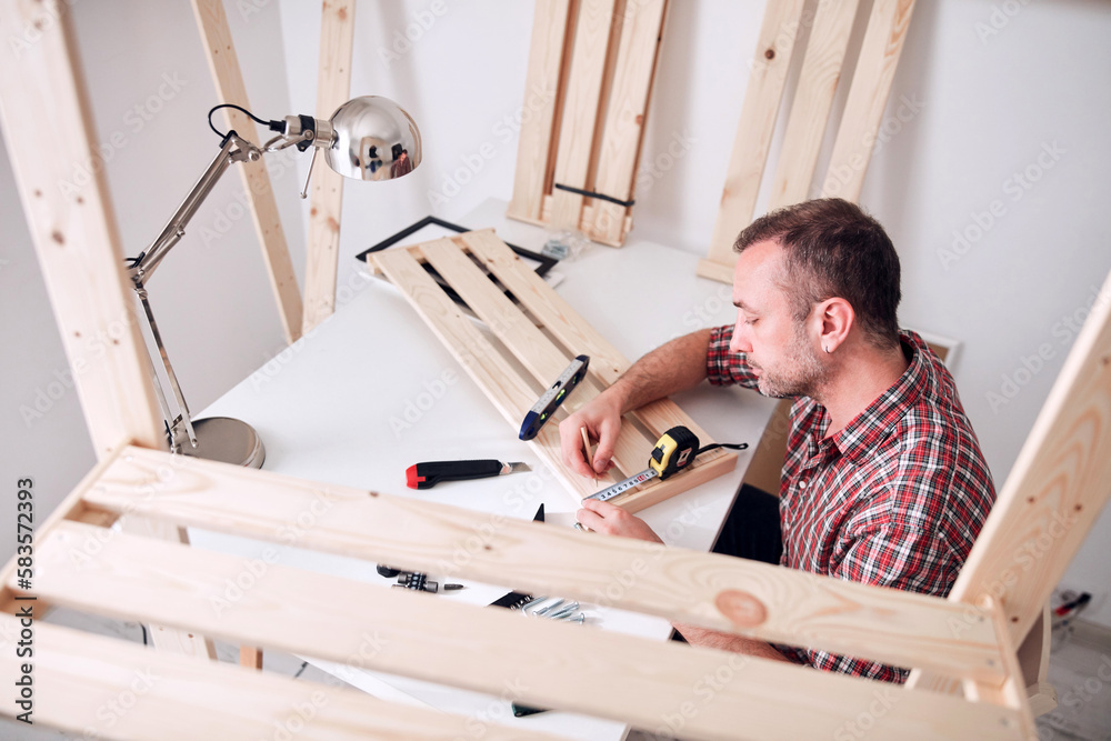 Obraz premium Man assembling new wooden shelf and furniture in the apartment.