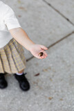 top view of cropped toddler girl in skirt holding acorn and standing on street.