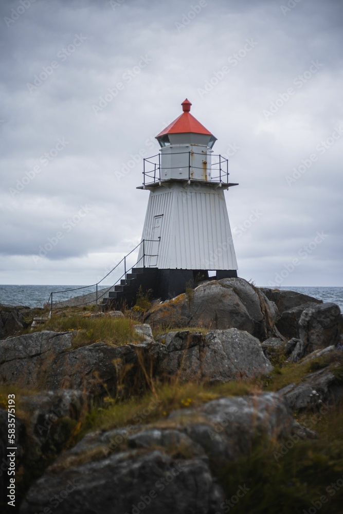 Vertical shot of a lighthouse on the rocky coast on a cloudy day