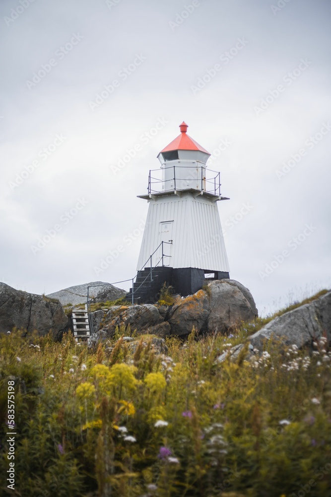 Vertical shot of a lighthouse on the rocky coast on a cloudy day