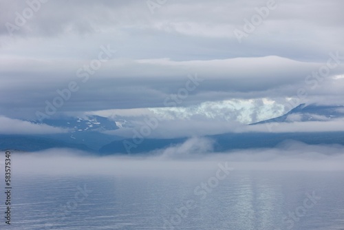 Minimalistic view of the fluffy white clouds over the calm sea © Jamo Images/Wirestock Creators