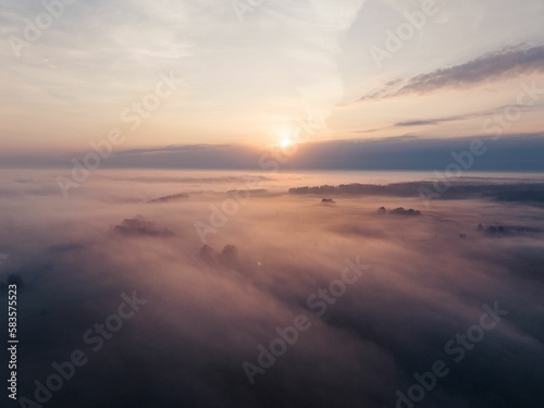 Aerial view of the landscape hardly visible because of the foggy weather at the purple sunset © Jamo Images/Wirestock Creators