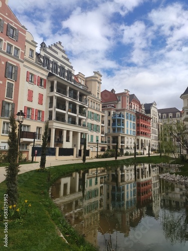 Zone de résidence moderne ou de logement neuf, avec un style ancien, baroque et tradition, tout coloré, en plein soleil, avec petit lac artificiel d'un vert limpide et beaucoup de plantes et verdure