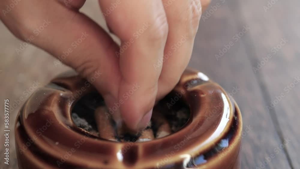Man putting out a smoking cigarette in an ashtray.