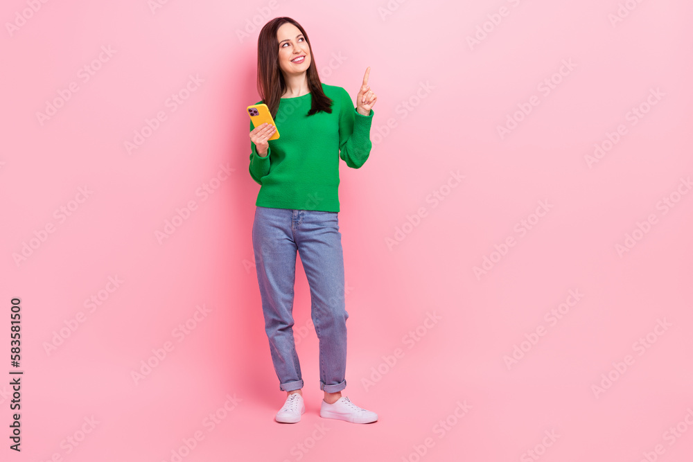 Full length portrait of charming nice person hold telephone look direct finger empty space isolated on pink color background Full length portrait of charming nice person hold telephone look direct finger empty space isolated on pink color background