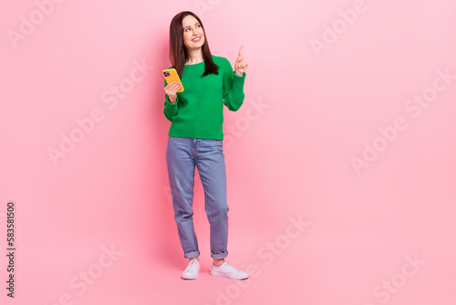 Full length portrait of charming nice person hold telephone look direct finger empty space isolated on pink color background