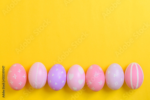 Happy easter holiday celebration concept. Group of painted colourful eggs decoration on a yellow background. Seasonal religion tradition design. Top view  flat lay  copy space.
