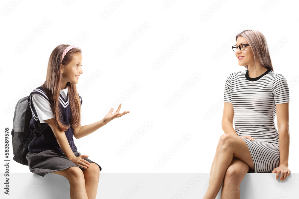 Schoolgirl sitting on a blank panel and talking to a young woman Schoolgirl sitting on a blank panel and talking to a young woman