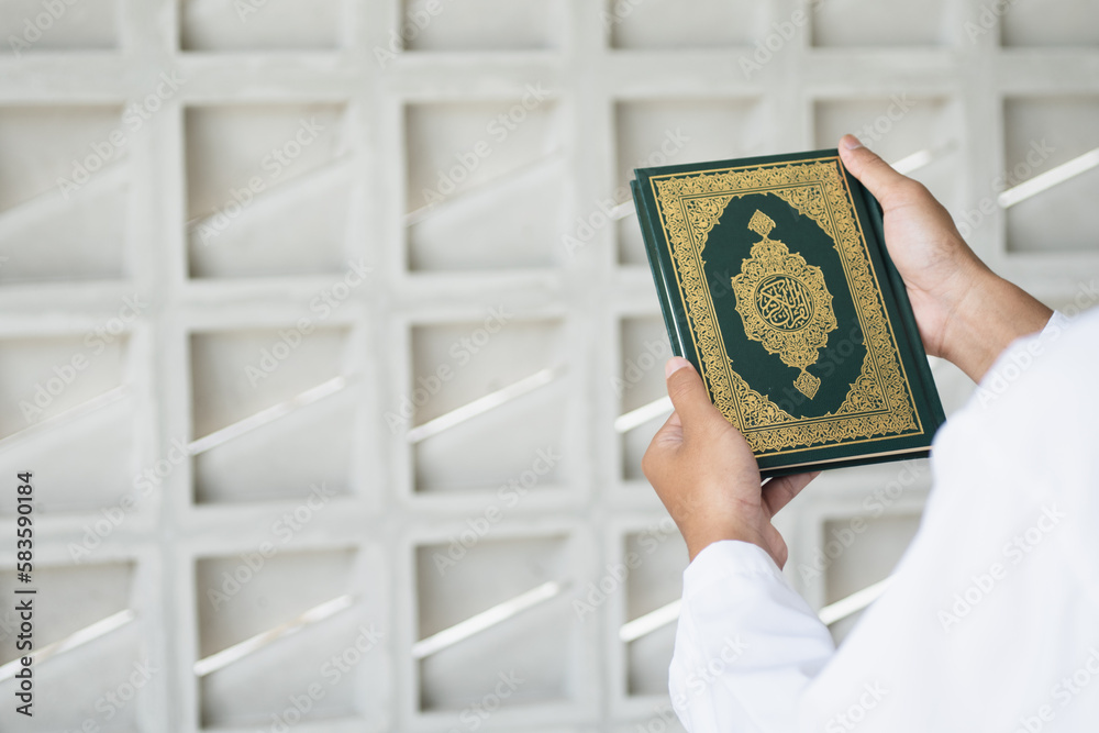 Holy Quran in Hand with arabic calligraphy meaning of Al Quran. Muslim