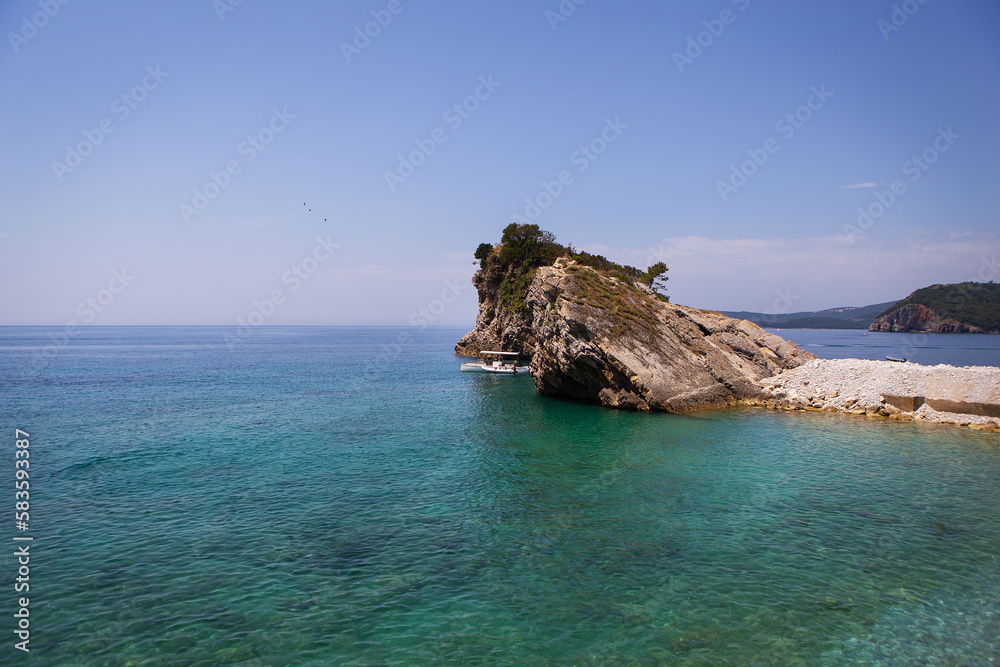 Very beautiful view of the sea and the rock, a small boat near the cliff, aquamarine clear water. Enjoy the view. Montenegro.