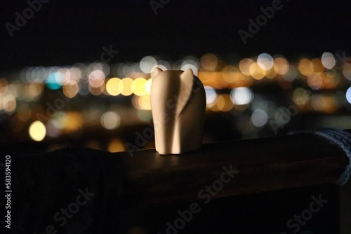 Selective focus of an elephant figurine on a wooden surface with a background of blurred city lights