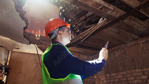 Building inspector. Man in a hard hat and a yellow reflective vest examines damaged structures and inspects the building. Damage assessment. Preparing for the repair or construction of a building photo