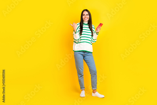 Photo of positive gorgeous lady wear stylish clothes look empty space offer modern device shop isolated on yellow color background