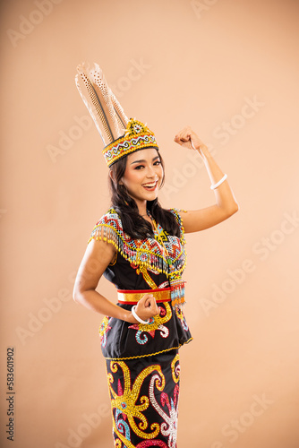 asian woman in traditional clothes of dayak tribe standing with smile and clenched her arms on isolated background