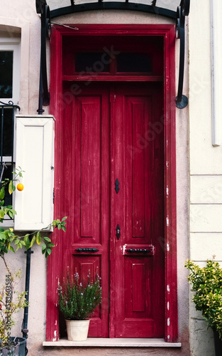 Entrance to the house with an old vintage wooden door in magenta color. photo