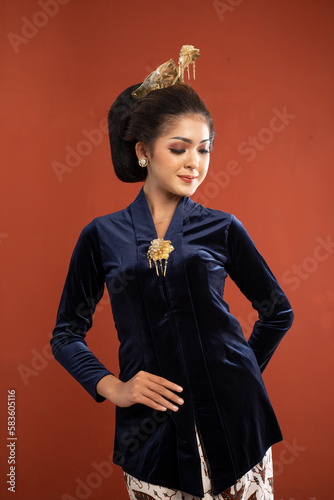 beautiful javanese woman in bludru kebaya standing put her hand behind and touch her kebaya on isolated background photo