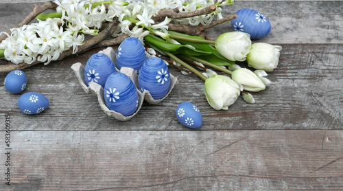 Ostern Hintergrund: Blaue Ostereier mit einem Blumenarrangement, bestehend aus Tulpen und Hyazinthen, auf einem Hintergrund aus abgenutztem Holz.