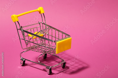 Mini shopping trolley on pink background