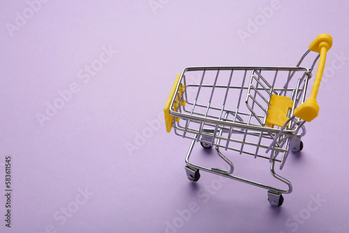 Mini shopping trolley on purple background