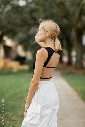 Fototapeta Naklejka Na Ścianę i Meble -  young woman in white cargo pants and trendy tank top standing on street in Miami.