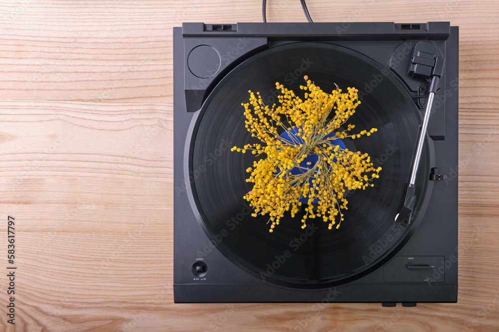 Top view of a black turntable with a playing vinyl record, on which, in