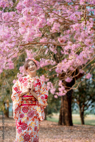 Asian lady in traditional kimono dress enjoy travel and holding dango near cherry blossom tree in spring festival. Emotion smile