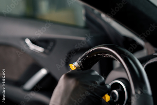 Worker cleans steering wheel professional brush and clout of microfiber Professional car wash and detailing Interior detailing © Guys Who Shoot