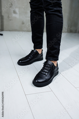 Close-up of male legs in black leather casual sneakers. Comfortable men's demi-season shoes