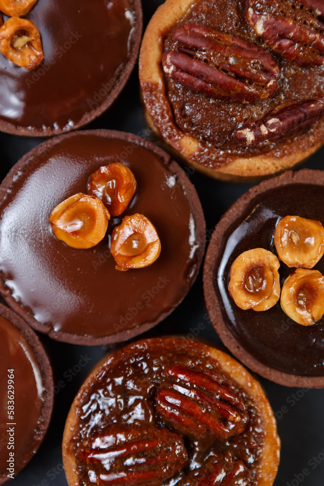 Little chocolate tarts in flat lay. Six tasty shortbread cakes with Belgian milk chocolate and nuts baked in a pastry cafe Little chocolate tarts in flat lay. Six tasty shortbread cakes with Belgian milk chocolate and nuts baked in a pastry cafe