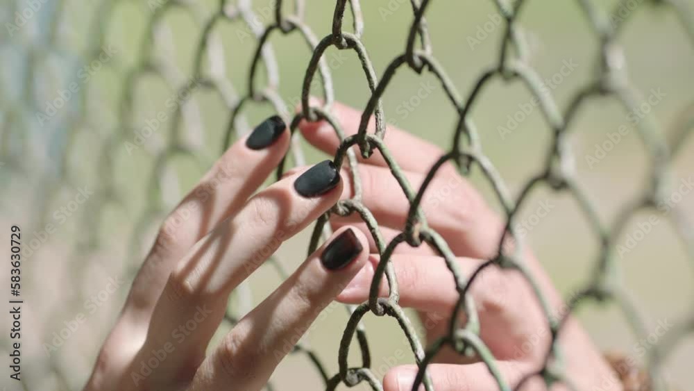 Two hands touching each other through the metal mesh of the fence. High quality HD footage Two hands touching each other through the metal mesh of the fence. High quality HD footage