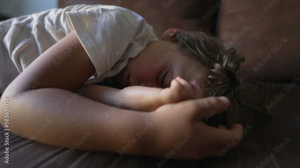 Sleeping child lying on couch napping. Kid in deep slumber asleep during afternoon nap. Cute tired little boy resting