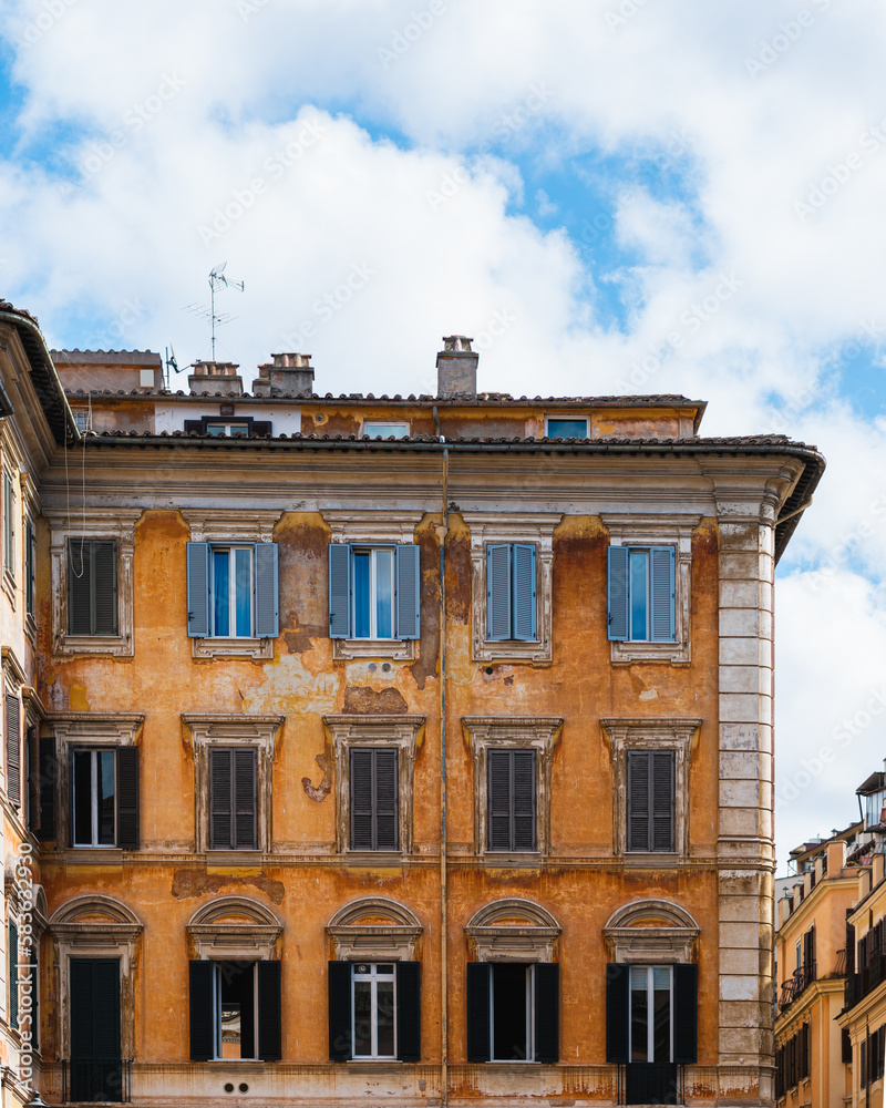 Obraz premium Photograph of an old yellow building in the city of Rome. The image shows only the building and the sky with some clouds in the background, creating a serene and quiet atmosphere.